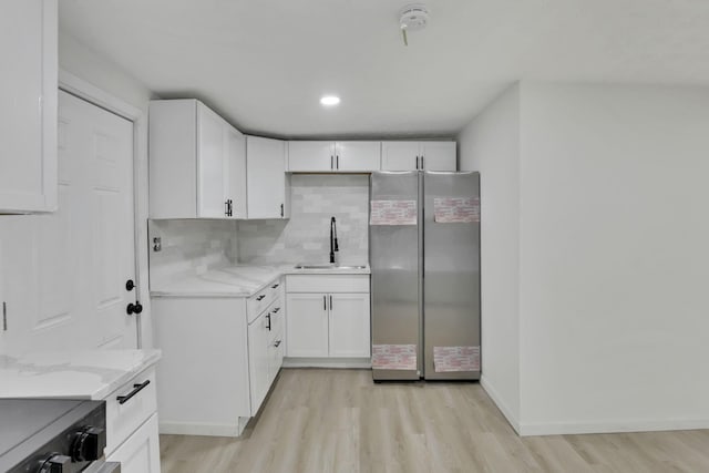 kitchen featuring backsplash, stainless steel fridge, sink, and white cabinets