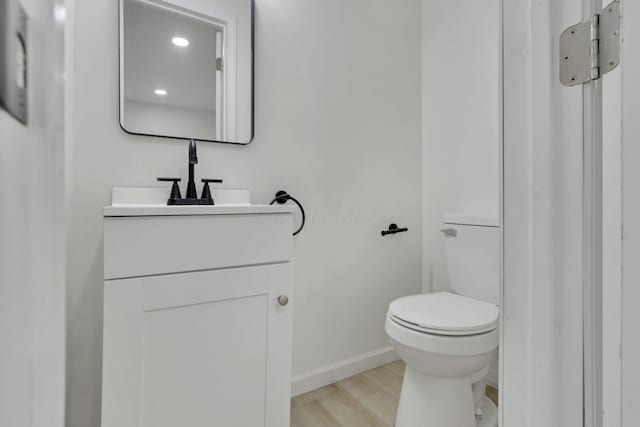 bathroom with hardwood / wood-style floors, vanity, and toilet