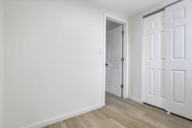 unfurnished bedroom with a closet and light wood-type flooring