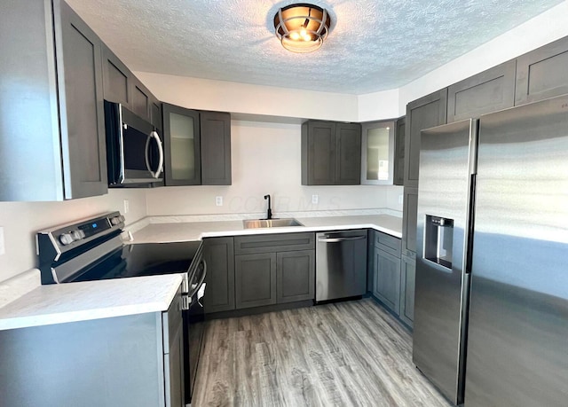 kitchen featuring a textured ceiling, sink, light wood-type flooring, and stainless steel appliances