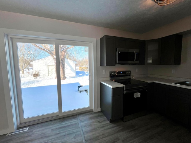 kitchen featuring black electric range oven, wood-type flooring, and a textured ceiling