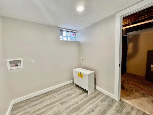 washroom with electric dryer hookup, hookup for a washing machine, light hardwood / wood-style floors, and a textured ceiling