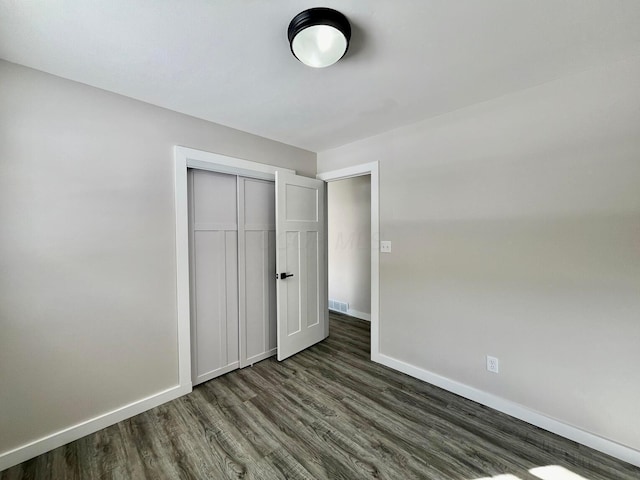 unfurnished bedroom featuring a closet and dark hardwood / wood-style floors