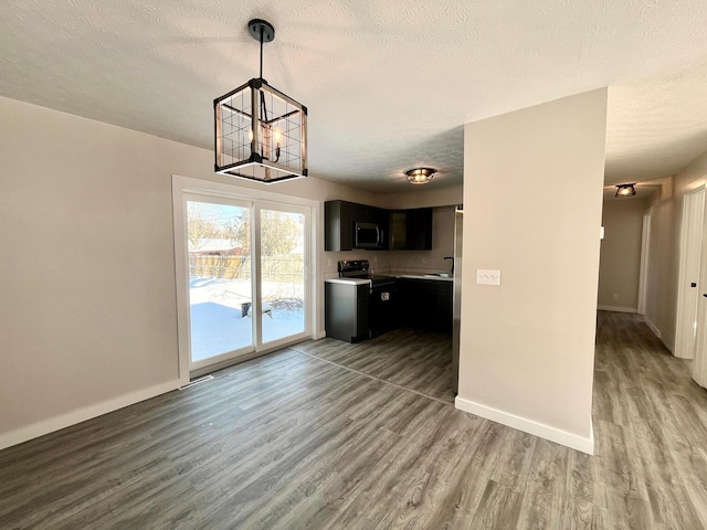 kitchen with hanging light fixtures, hardwood / wood-style flooring, range with electric stovetop, a textured ceiling, and a notable chandelier