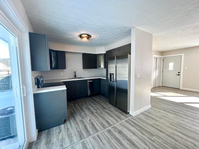 kitchen featuring sink, light hardwood / wood-style floors, a textured ceiling, and appliances with stainless steel finishes