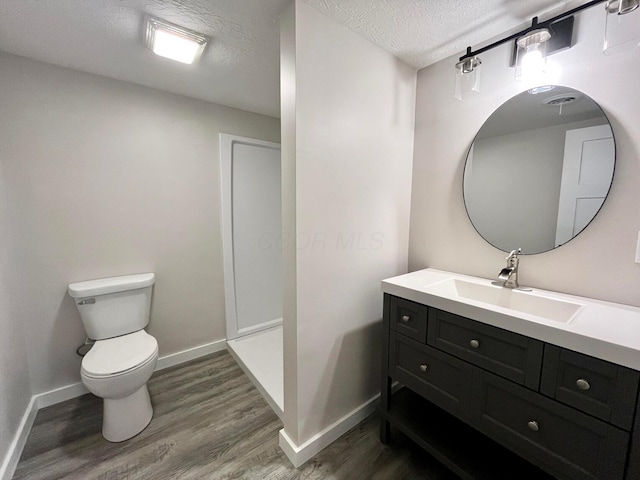 bathroom featuring hardwood / wood-style flooring, vanity, toilet, and a textured ceiling