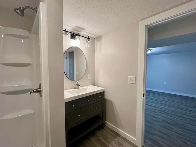 bathroom with hardwood / wood-style flooring, vanity, a textured ceiling, and walk in shower