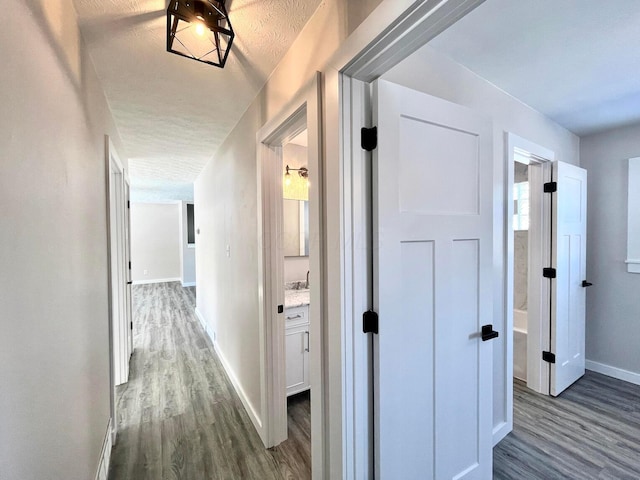 corridor with dark hardwood / wood-style floors and a textured ceiling