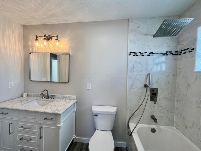 full bathroom featuring hardwood / wood-style floors, vanity, tiled shower / bath combo, toilet, and a textured ceiling