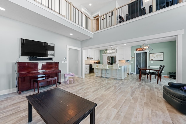 living room featuring a chandelier, a high ceiling, and light wood-type flooring