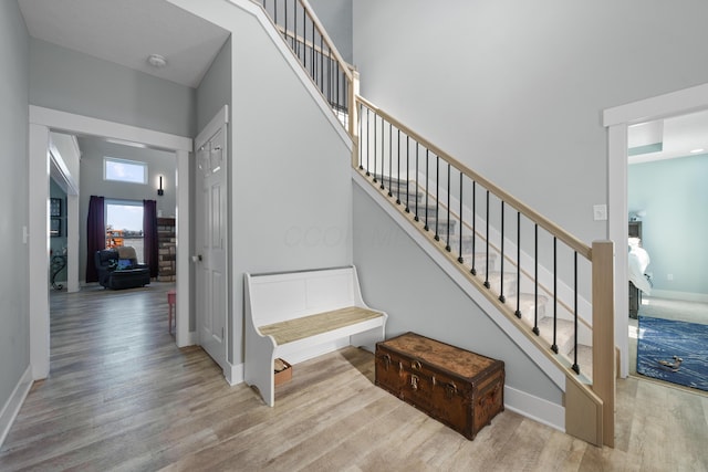 staircase with hardwood / wood-style floors and a towering ceiling