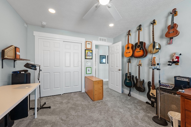 carpeted home office with ceiling fan and a textured ceiling