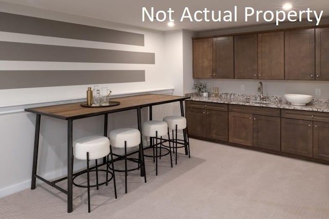 kitchen with dark brown cabinetry, butcher block countertops, sink, and a breakfast bar