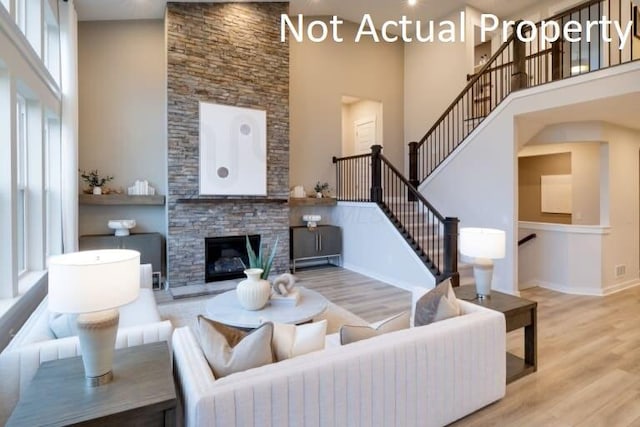 living room featuring hardwood / wood-style floors, a fireplace, and a high ceiling