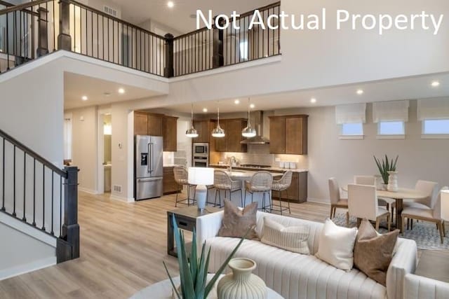 living room featuring a towering ceiling and light hardwood / wood-style floors