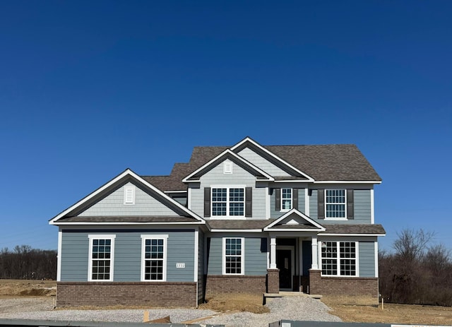 craftsman house featuring brick siding and a shingled roof