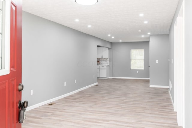 interior space with a textured ceiling and light hardwood / wood-style flooring