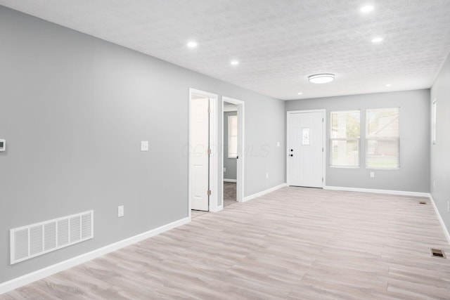 unfurnished room featuring a textured ceiling and light hardwood / wood-style flooring