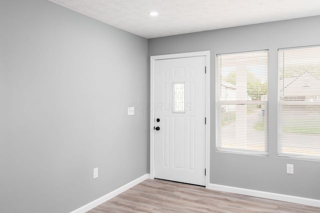 foyer with a textured ceiling and light hardwood / wood-style floors