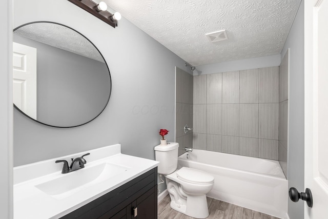 full bathroom with hardwood / wood-style floors, a textured ceiling, toilet, vanity, and bathtub / shower combination