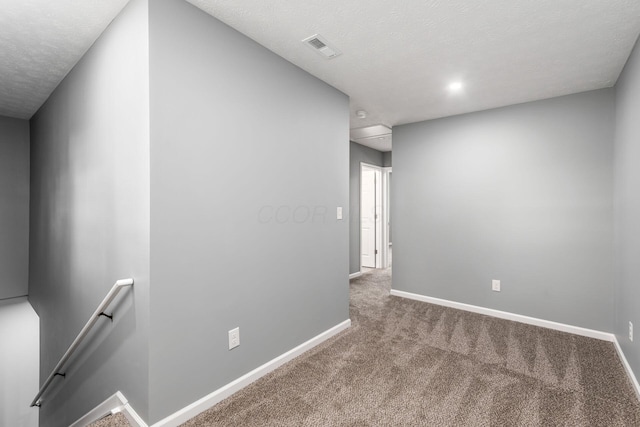 spare room featuring carpet and a textured ceiling