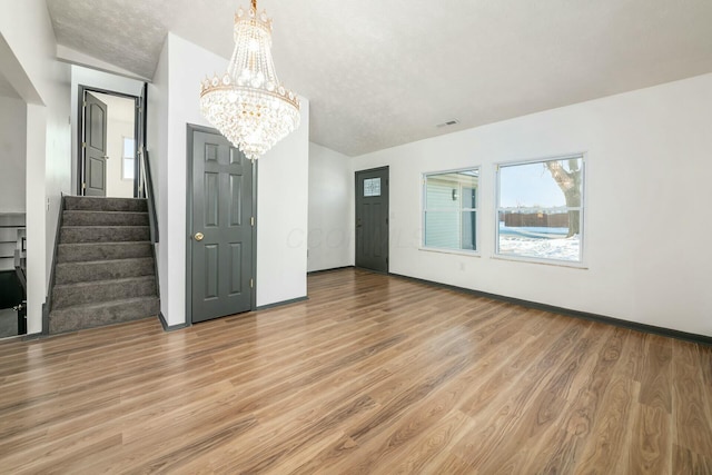 unfurnished living room featuring a chandelier, hardwood / wood-style flooring, and vaulted ceiling