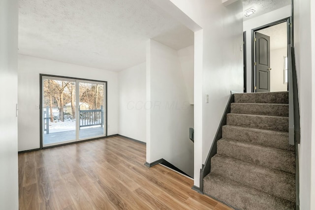 stairs with wood-type flooring and a textured ceiling