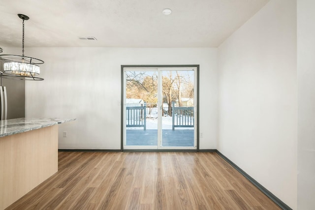 unfurnished dining area with light hardwood / wood-style flooring and a notable chandelier