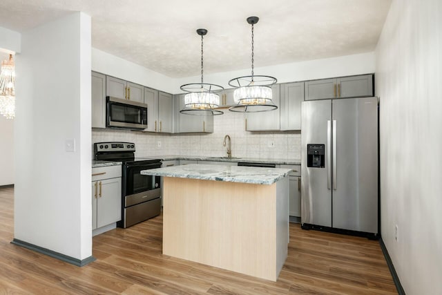 kitchen featuring a center island, sink, light stone counters, appliances with stainless steel finishes, and dark hardwood / wood-style flooring