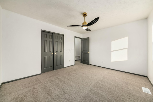 unfurnished bedroom with a textured ceiling, ceiling fan, and light carpet