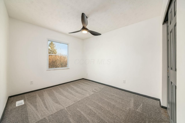 carpeted spare room featuring ceiling fan and a textured ceiling