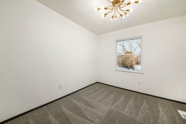 carpeted empty room featuring a textured ceiling and an inviting chandelier