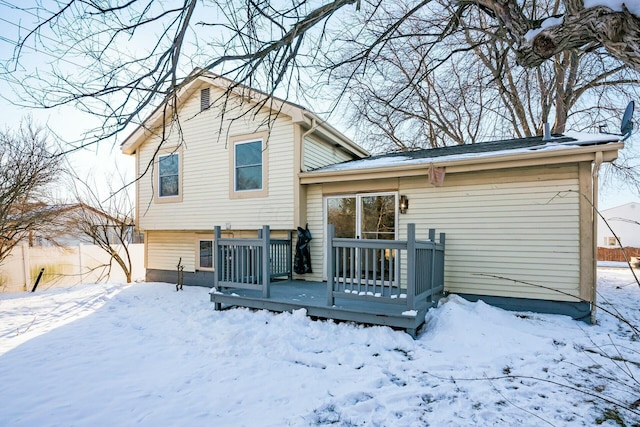 snow covered back of property with a wooden deck