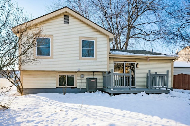 snow covered rear of property featuring central AC and a wooden deck