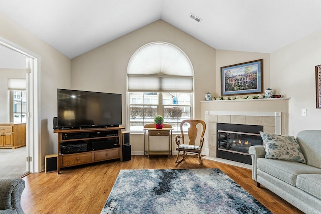 living room featuring a fireplace, light hardwood / wood-style floors, and vaulted ceiling