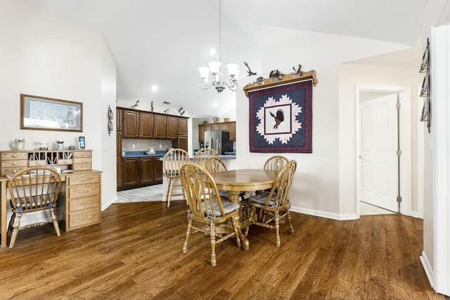 dining area featuring lofted ceiling, dark wood-type flooring, and a chandelier