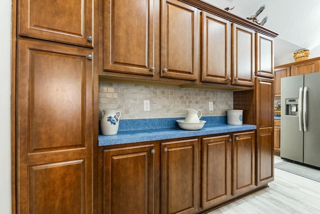 kitchen with light hardwood / wood-style floors, stainless steel fridge with ice dispenser, and backsplash