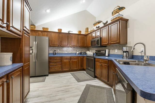 kitchen featuring stainless steel appliances, tasteful backsplash, sink, and light wood-type flooring