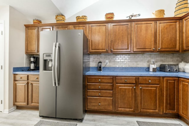 kitchen featuring vaulted ceiling, light hardwood / wood-style flooring, stainless steel fridge, and decorative backsplash