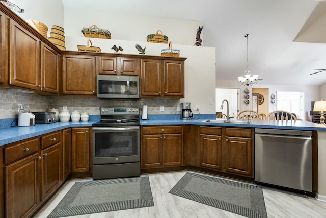 kitchen with sink, appliances with stainless steel finishes, tasteful backsplash, light hardwood / wood-style floors, and decorative light fixtures