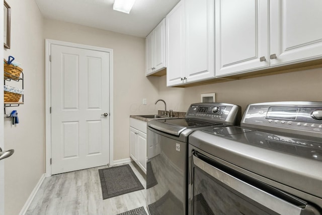 washroom with cabinets, sink, washer and dryer, and light hardwood / wood-style flooring