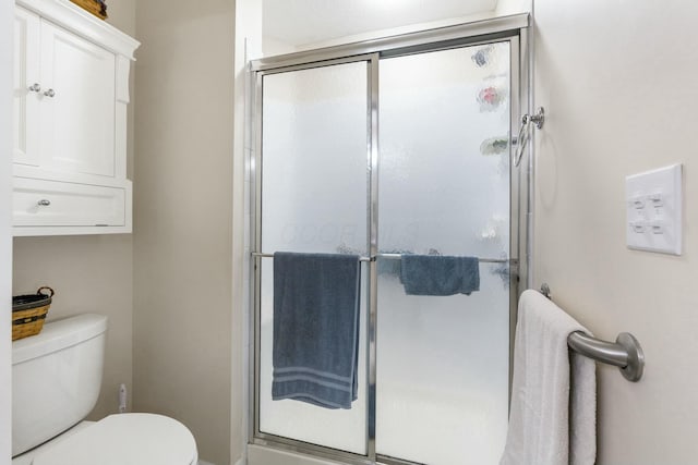 bathroom featuring a shower with shower door and toilet