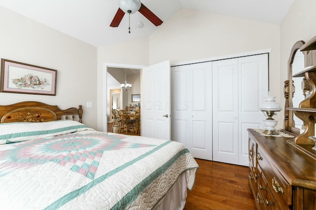 bedroom with dark hardwood / wood-style flooring, ceiling fan with notable chandelier, vaulted ceiling, and a closet