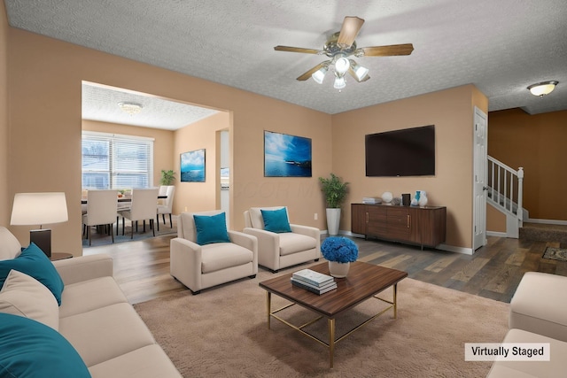 living room featuring ceiling fan, wood-type flooring, and a textured ceiling