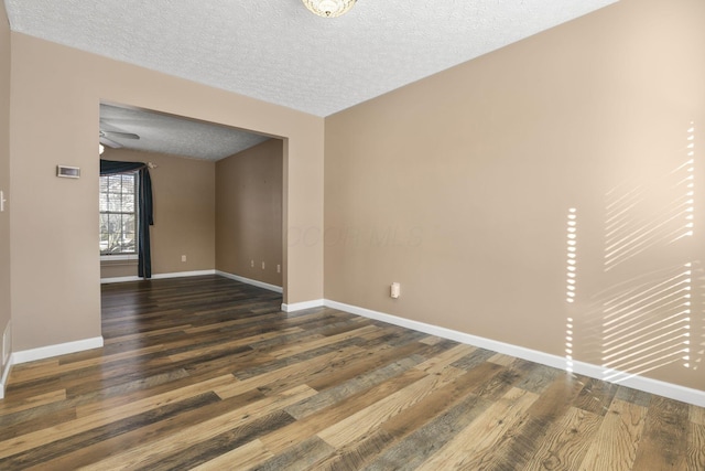 empty room with dark wood-type flooring and a textured ceiling