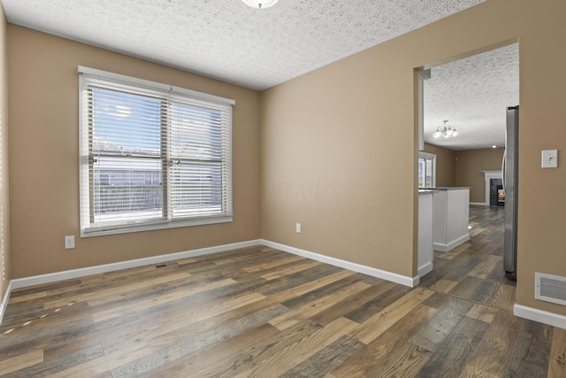 empty room with dark wood-type flooring and a textured ceiling