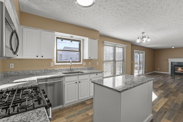 kitchen with white cabinetry, sink, a center island, stainless steel appliances, and a textured ceiling