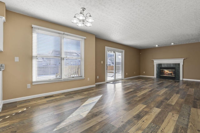 unfurnished living room featuring dark wood-type flooring, an inviting chandelier, a textured ceiling, and a fireplace