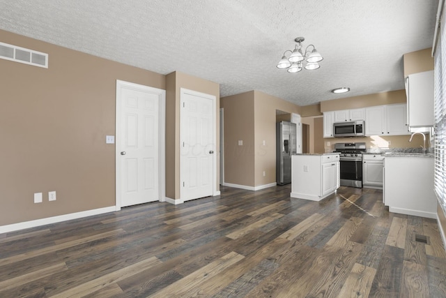 kitchen featuring a textured ceiling, dark wood-type flooring, stainless steel appliances, and white cabinets