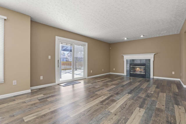 unfurnished living room with dark hardwood / wood-style flooring, a tiled fireplace, and a textured ceiling